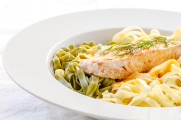 Lachsfilet auf grünen und hellen Bandnudeln