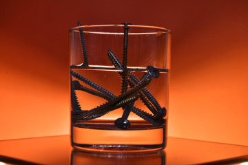 Fototapeta na wymiar glass with screws on an orange background