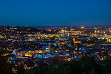 Fototapeta na wymiar Germany, Illuminated magical skyline of downtown stuttgart city houses, buildings and churches seen from above by night after sunset