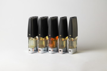 e-juice vape refill pods with liquids of different shades of orange yellow, white background isolated close up