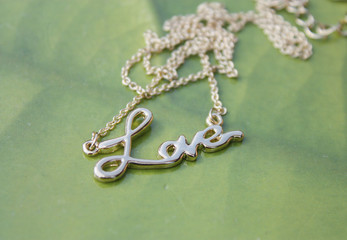 A precious jewel is a white gold bracelet with an inscription love. The word "Love" on a chain.