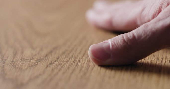 Slow motion man hand touch oil finished oak wood surface