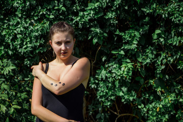 Young beautiful girl in black dress with tattoo on her hand in the park 