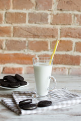 Sweet chocolate cookies with vanilla cream filling and a glass of milk.