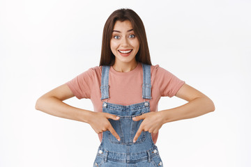 Cheerful lovely caucasian girl sharing link to awesome product, pointing fingers down recommend...