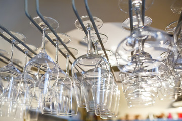 rows of empty glasses hang on reception party table in bar. Close up at row of glasses prepare to service for dinner party