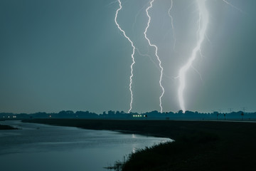 Naklejka na ściany i meble Extremely bright lightning bolt near a river in the Netherlands
