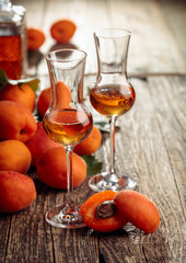 Apricot liquor and fresh apricots on a old wooden table.