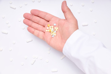 A hand of a Doctor with pills, medicines and bottles of medicines on a white background. pharmacy medicines.