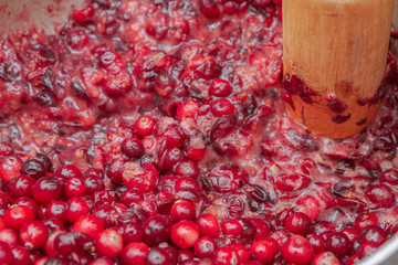 Crush the red cranberry berries with a wooden rolling pin