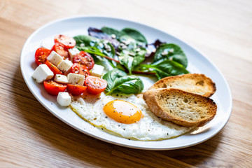 Breakfast - fried egg, toasts and vegetable salad