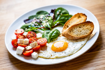 Breakfast - fried egg, toasts and vegetable salad