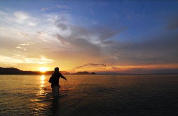 Casting net against sea, blue sky at sunset