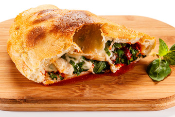 Pizza calzone on cutting board on white background