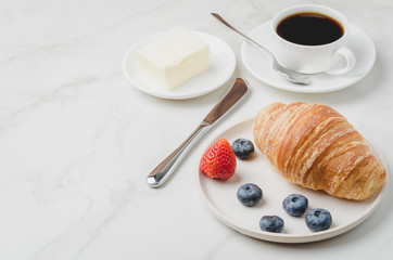 Delicious breakfast with fresh coffee, fresh croissants and berries on a white table. Selective focus and copy space.