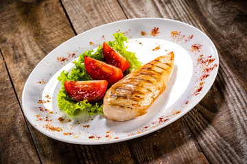 Grilled chicken fillet and vegetables on white plate