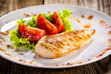 Grilled chicken fillet and vegetables on white plate