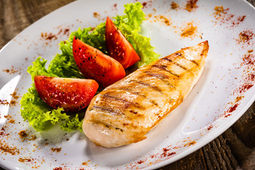 Grilled chicken fillet and vegetables on white plate