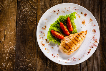 Grilled chicken fillet and vegetables on white plate