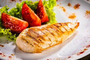Grilled chicken fillet and vegetables on white plate