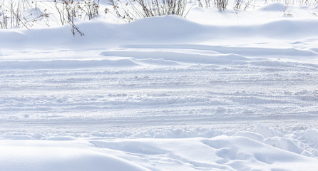 Traces of a car on white snow as a background