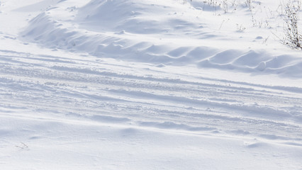 Traces of a car on white snow as a background