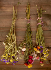 Three bouquets of dried flowers hang on the wooden wall.