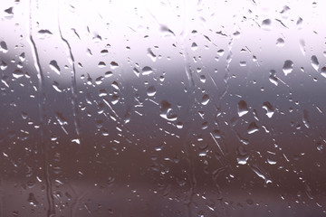 Drops of water on window glass after rain with dramatic blurred sunset on background. Idyllic tranquil nature wallpaper.