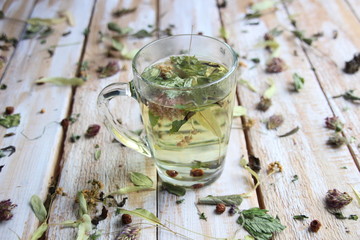 Herbs floating in hot water in glass with wooden background