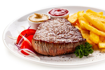 Grilled steaks, French fries and vegetables