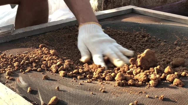 Close up shot of sifting through dry clay for building simple house of adobe airbricks