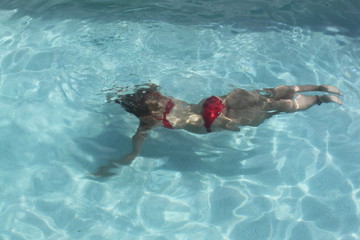 Frau taucht im Swimmingpool im Urlaub