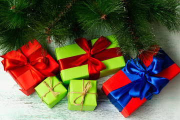 Gift boxes on a wooden light background near fir branches. Christmas composition