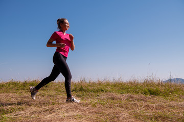 Fototapeta na wymiar young woman jogging on sunny day at summer mountain