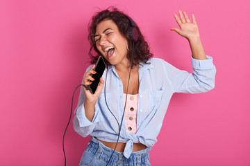 Close up portrait of young girl listening, enjoying music and holding cellular mp3 player in hand...