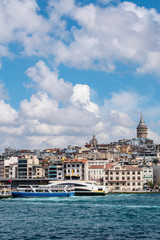 Fototapeta premium Istanbul, Turkey: the breathtaking skyline with the Galata Tower and a ship crossing the Bosphorus for a cruise in the Strait of Istanbul, part of the continental boundary between Europe and Asia