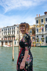 Fototapeta na wymiar Caucasian redhead woman with floral dress looking at grand canal Venice smiling