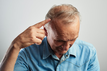 Fototapeta premium Pensioner points a finger at a gray-haired balding head isolated on a white background. The problem of hair loss, androgenic alopecia