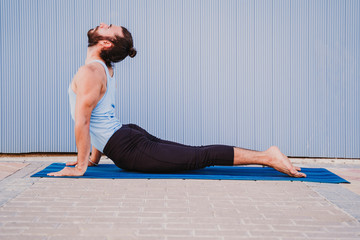 man in the city practicing yoga sport. blue background. healthy lifestyle