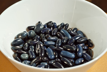 Many beans are sorted by species. Fresh young beans in a white plate. Texture of black and dark blue beans. The concept of union and grouping, friendship and reunion.