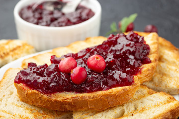 Cranberries jam. Crispy sandwich with cranberry sauce on dark background.