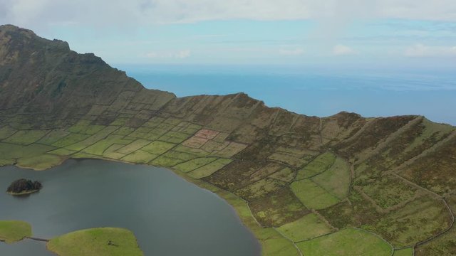 Flying towards the world's end. Green slope of caldera and ocean behind the vlocano. Aerial of Corvo, Azores