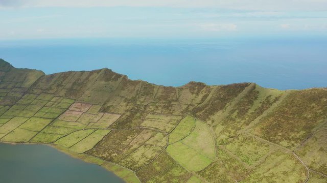 Mountain on a sea shore. Green lined slopes of ridge and lake in caldera. Aerial of Corvo island, Azores