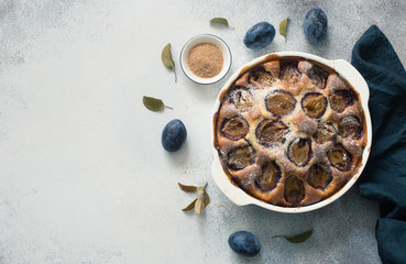Rustic plum cake on a grey stone background
