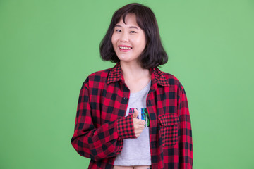Fototapeta premium Portrait of happy Asian hipster woman giving thumbs up