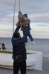 cute girl plays on the seashore, winter. Walk with your parents.