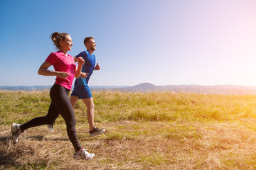 young couple jogging on sunny day at summer mountain