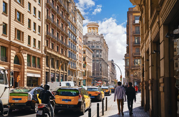 Barcelona, Spain. Wide street avenue with yellow cars taxi and high buildings. Traffic jam in centre of grand city. Cityscape sunny day.