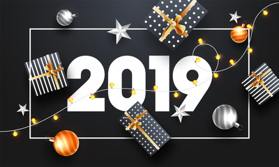 Top view of New Year poster or banner design with 2019 lettering, gift boxes and baubles on black background.