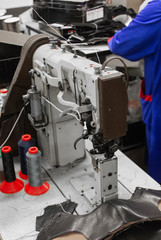 Professional sewing machine with black thread on a shoes factory.